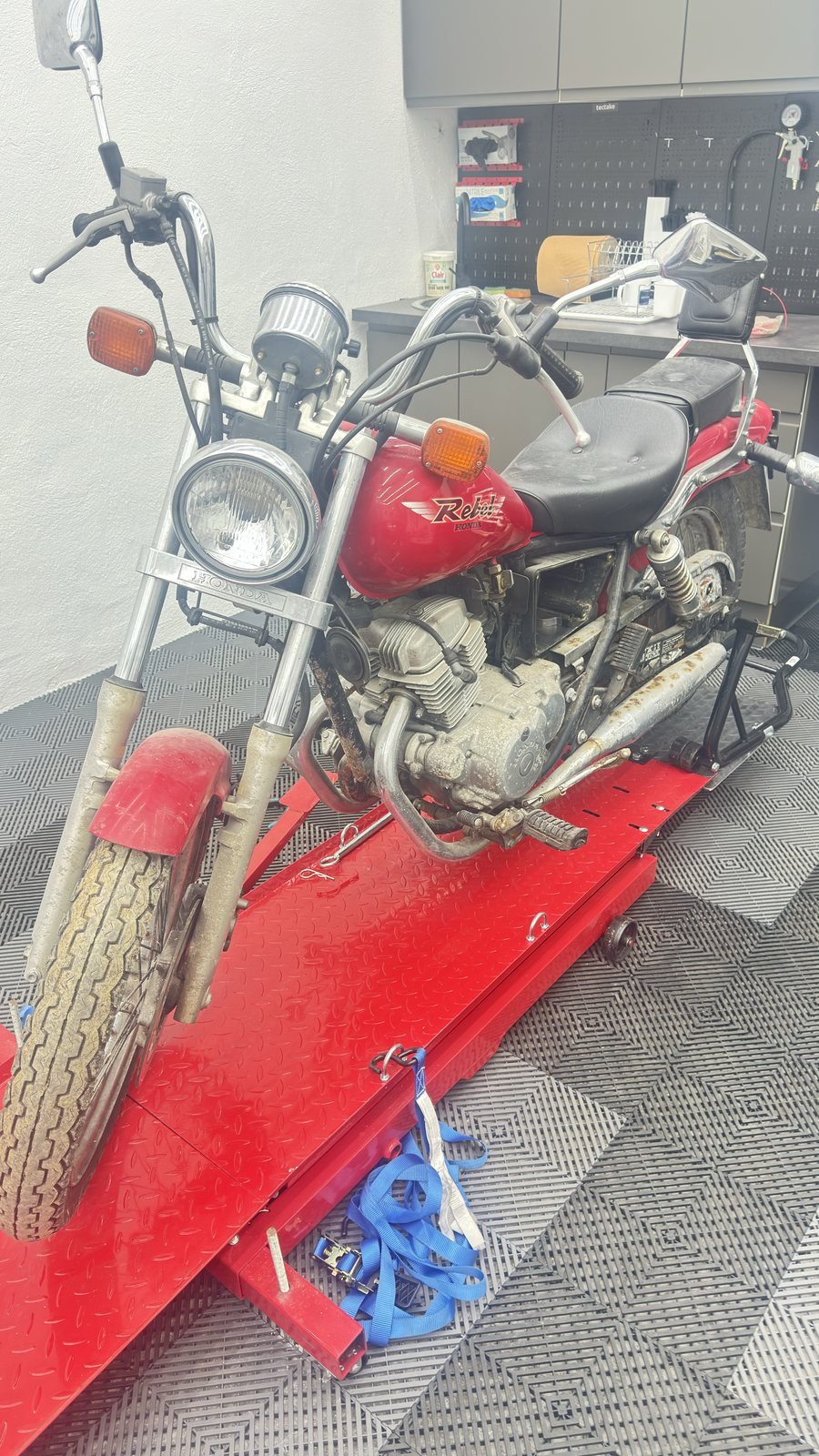 Moto ancienne rouge examinée pour établir un devis de remise en état